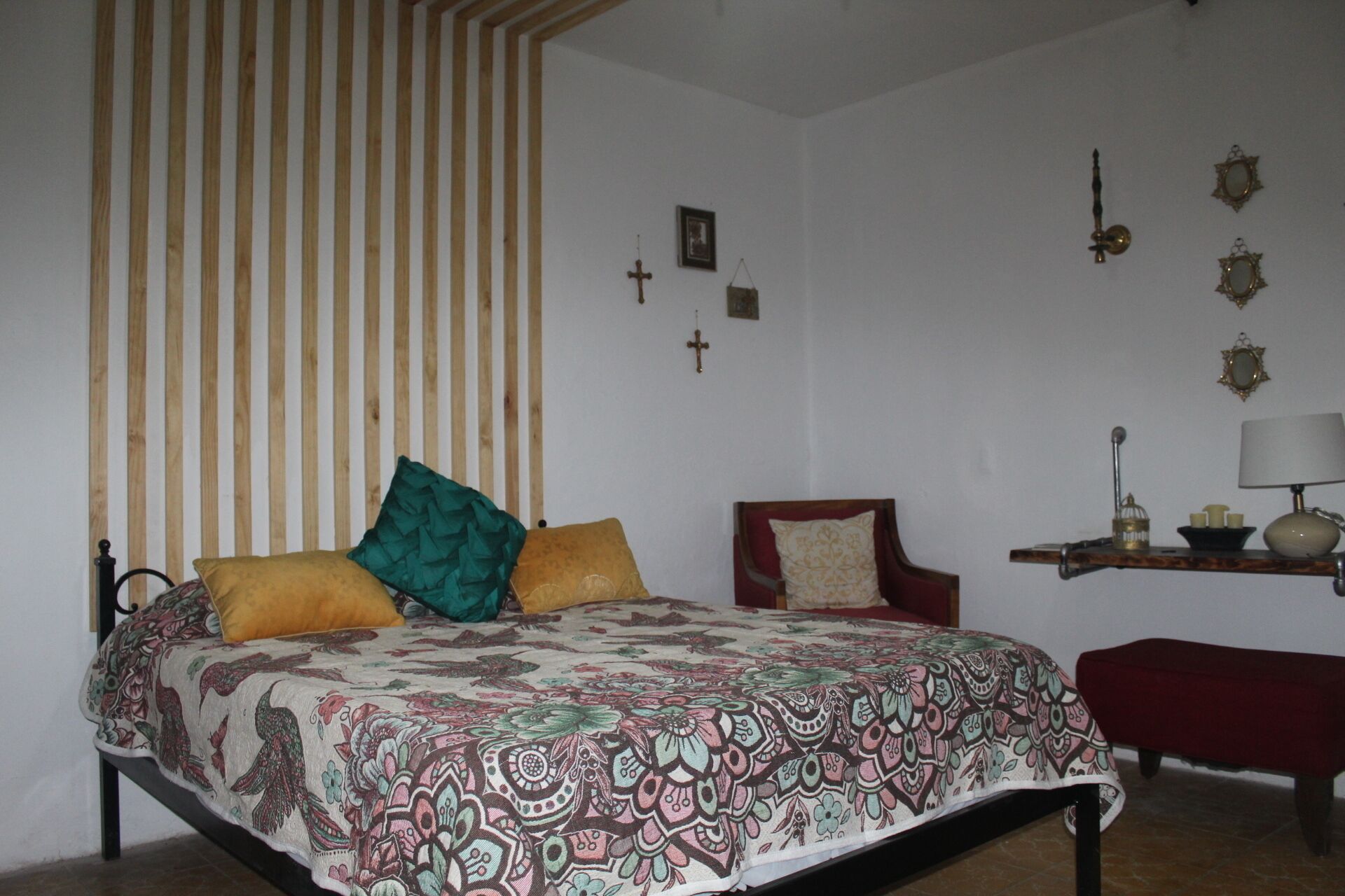 A bedroom with a bed, a chair, a nightstand, and a lamp.