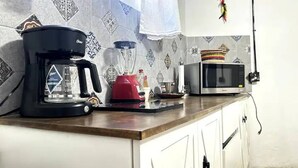 A kitchen with a coffee maker, a red kettle, a microwave, and a blender on the counter. - Fast Wi-Fi•Rooftop Lounge•Washer•Parián•Secure (San Pedro Tlaquepaque)