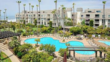 A resort with a large pool, palm trees, and a view of the ocean.