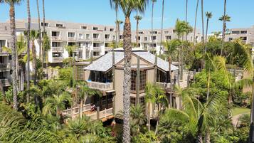 A hotel with multiple floors, balconies, and lush greenery including palm trees.