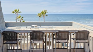 Eine Terrasse mit Blick auf den Ozean, ausgestattet mit einem Tisch und vier Korbstühlen.