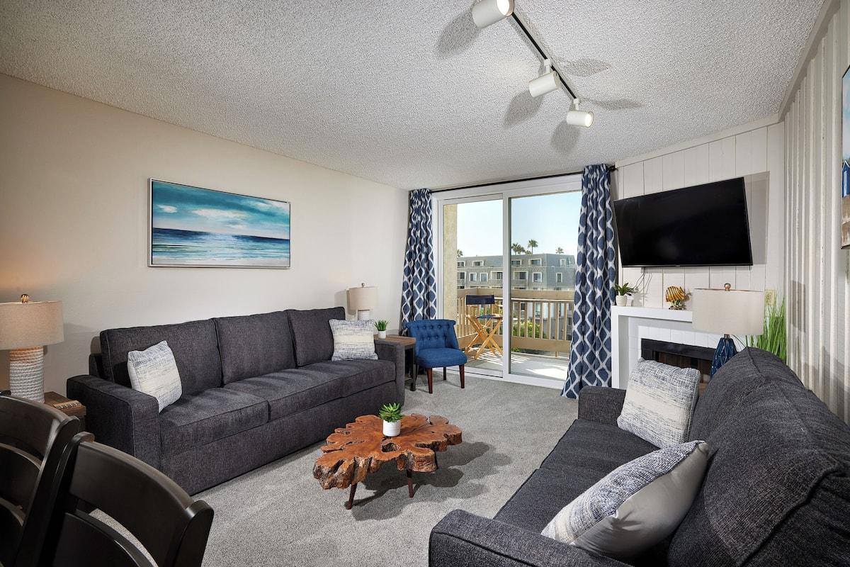 A living room with a grey sofa, a wooden coffee table, and a TV mounted on the wall.
