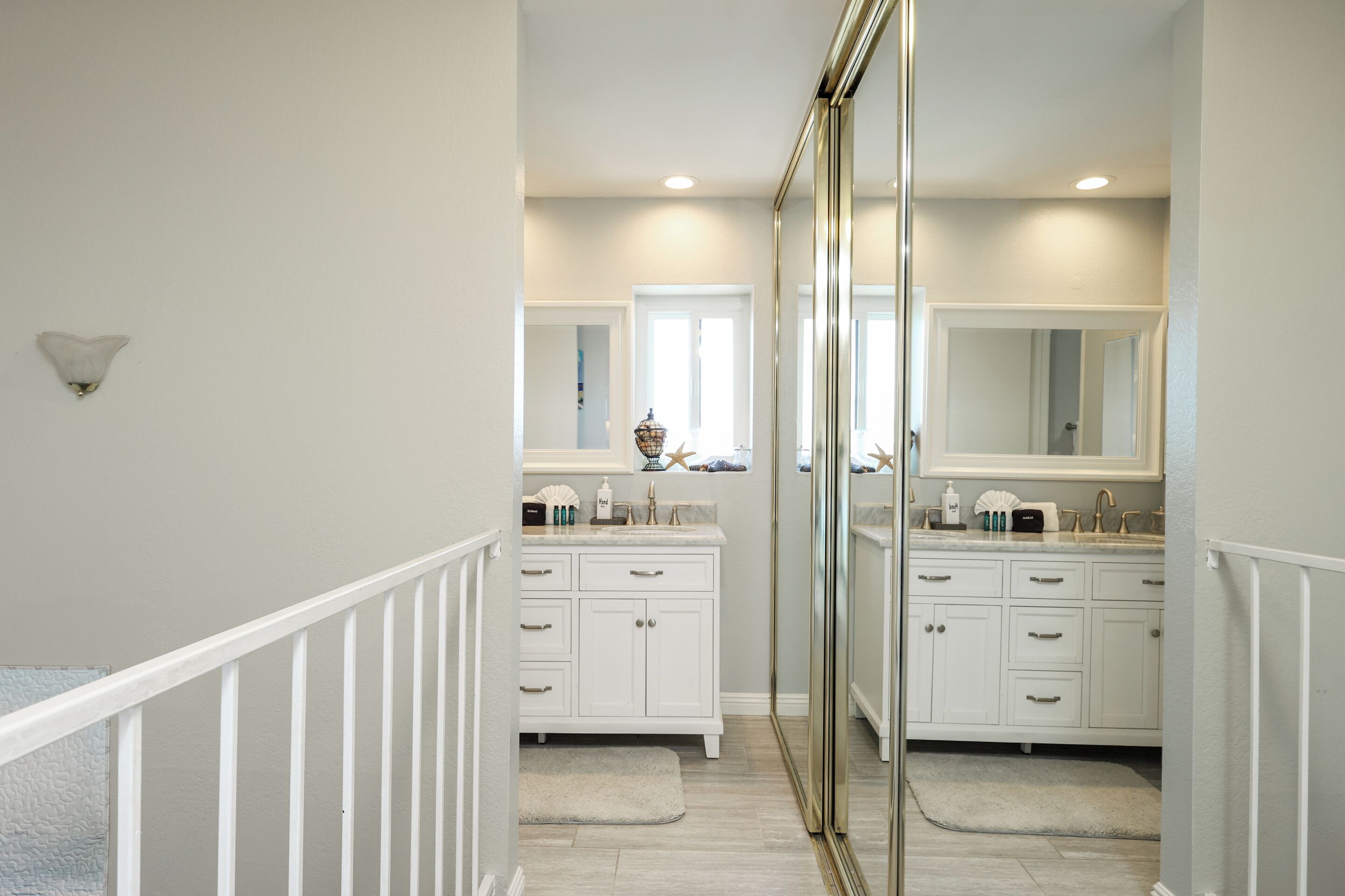 A modern bathroom with white cabinetry, a large mirror, and a glass shower enclosure.