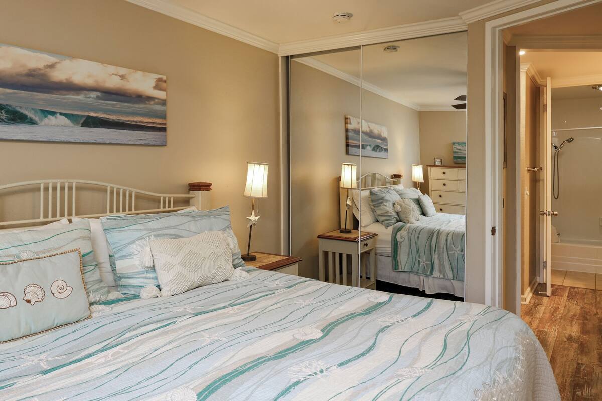 A bedroom with a bed, nightstands, a dresser, and a mirror.