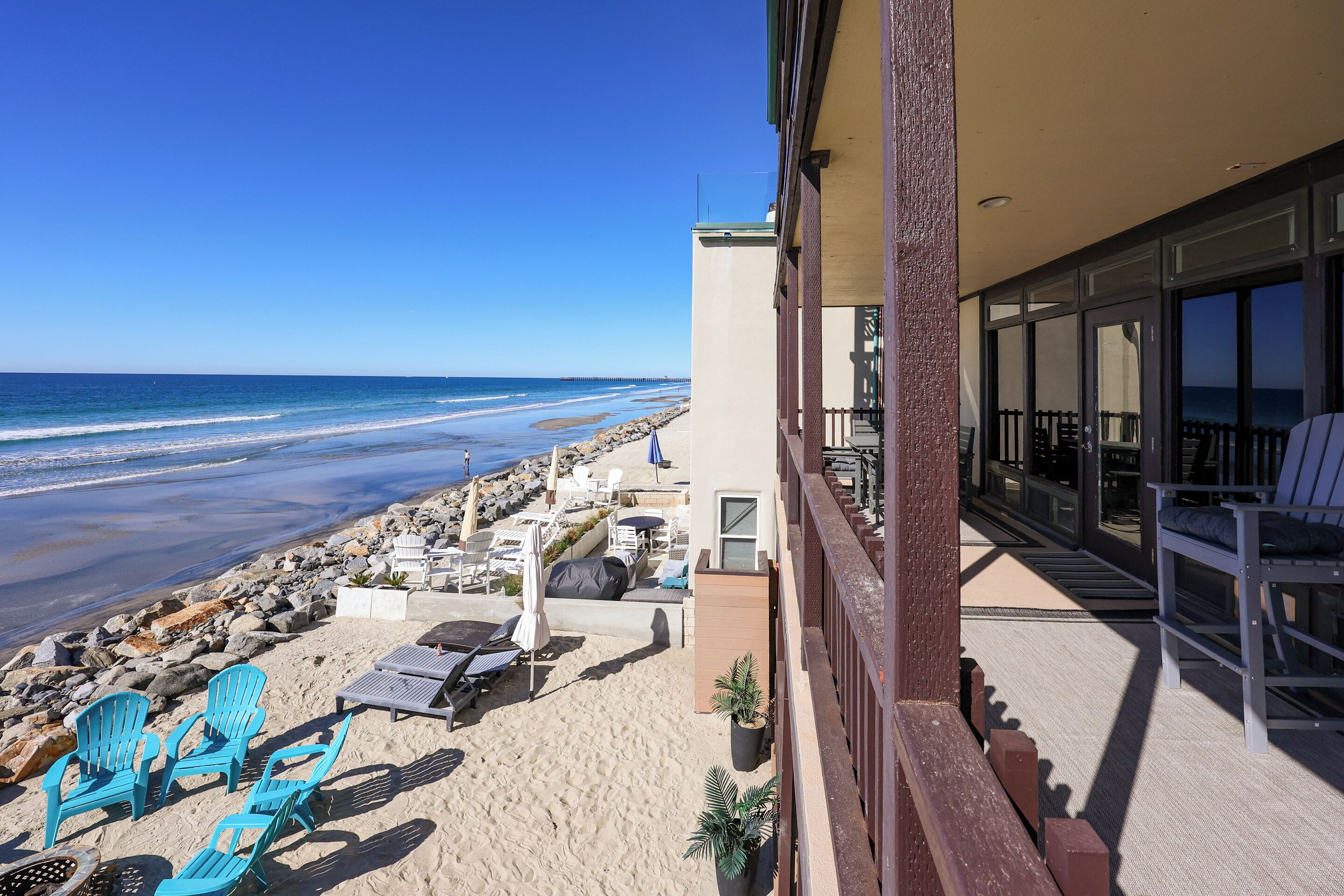 Ein Balkon am Strand mit Blick auf das Meer, Liegestühle und Sonnenschirme.