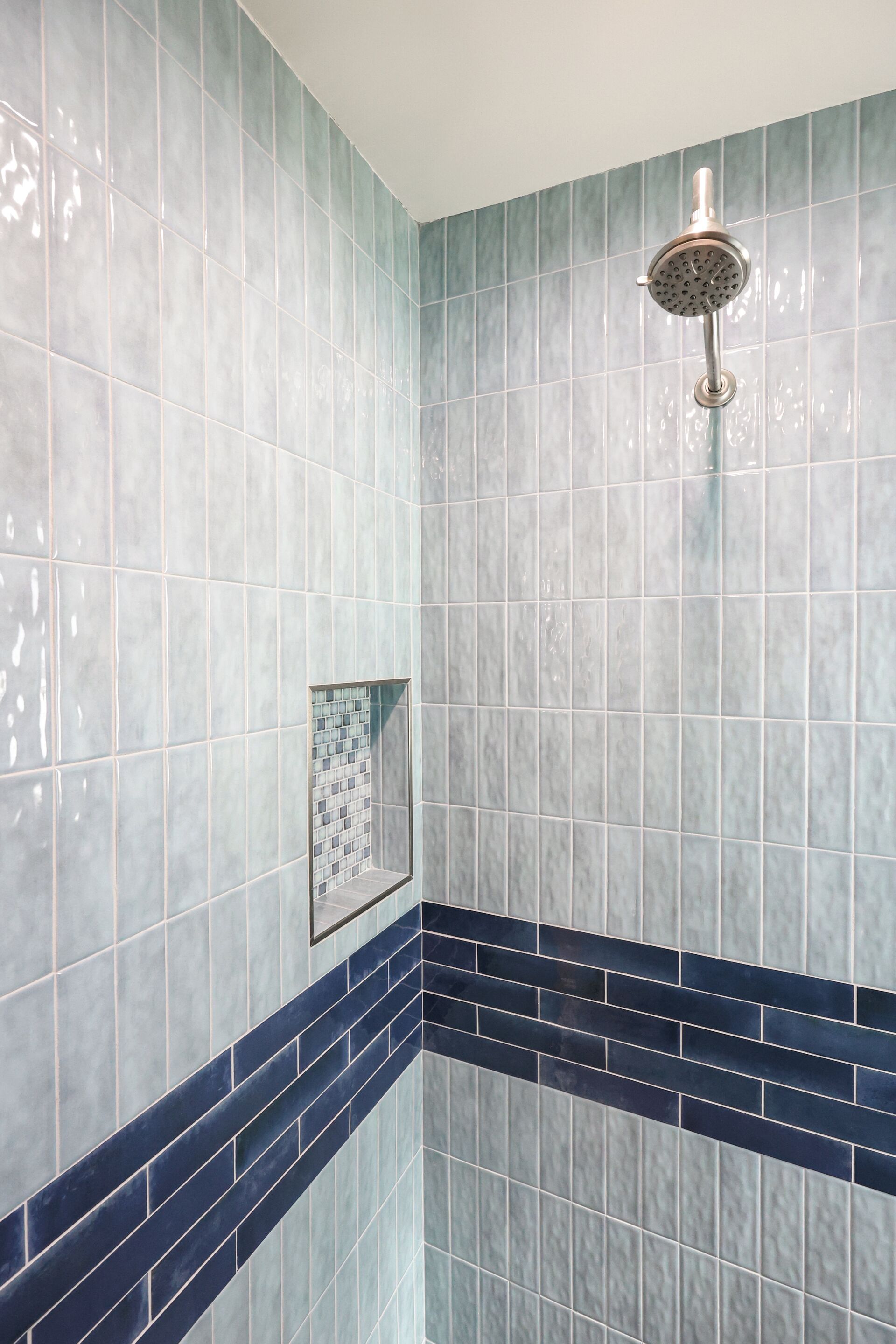 Un baño con azulejos azul claro y un borde azul oscuro.