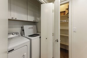 Zona de lavandería con lavadora y secadora Maytag, un armario blanco y la puerta de un closet entreabierta.