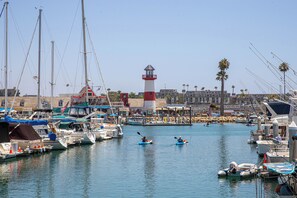 A marina with boats, a lighthouse, and a building with a red and white tower. - Oceanside Beach Condos (Oceanside)