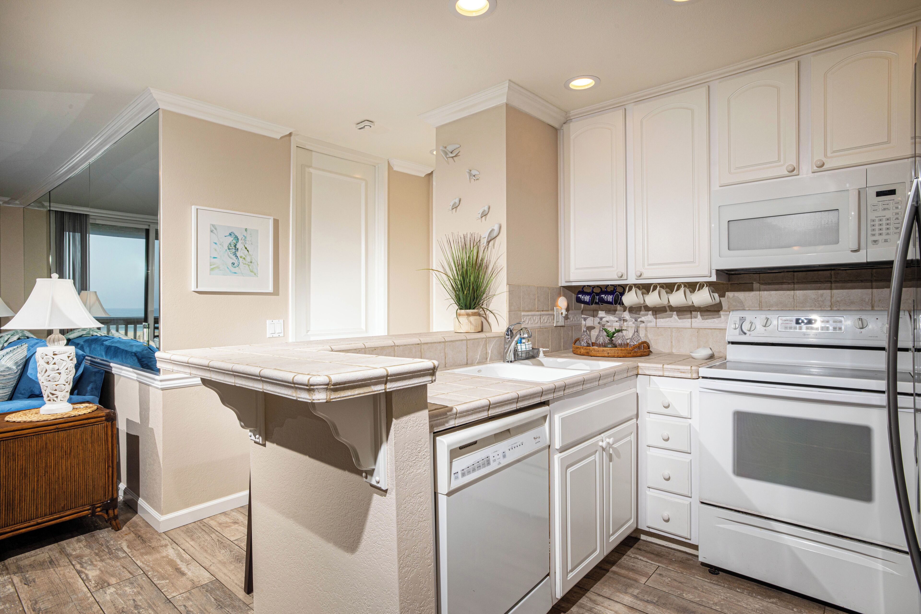 A kitchen with white cabinetry, a built-in dishwasher, a microwave, and an oven.