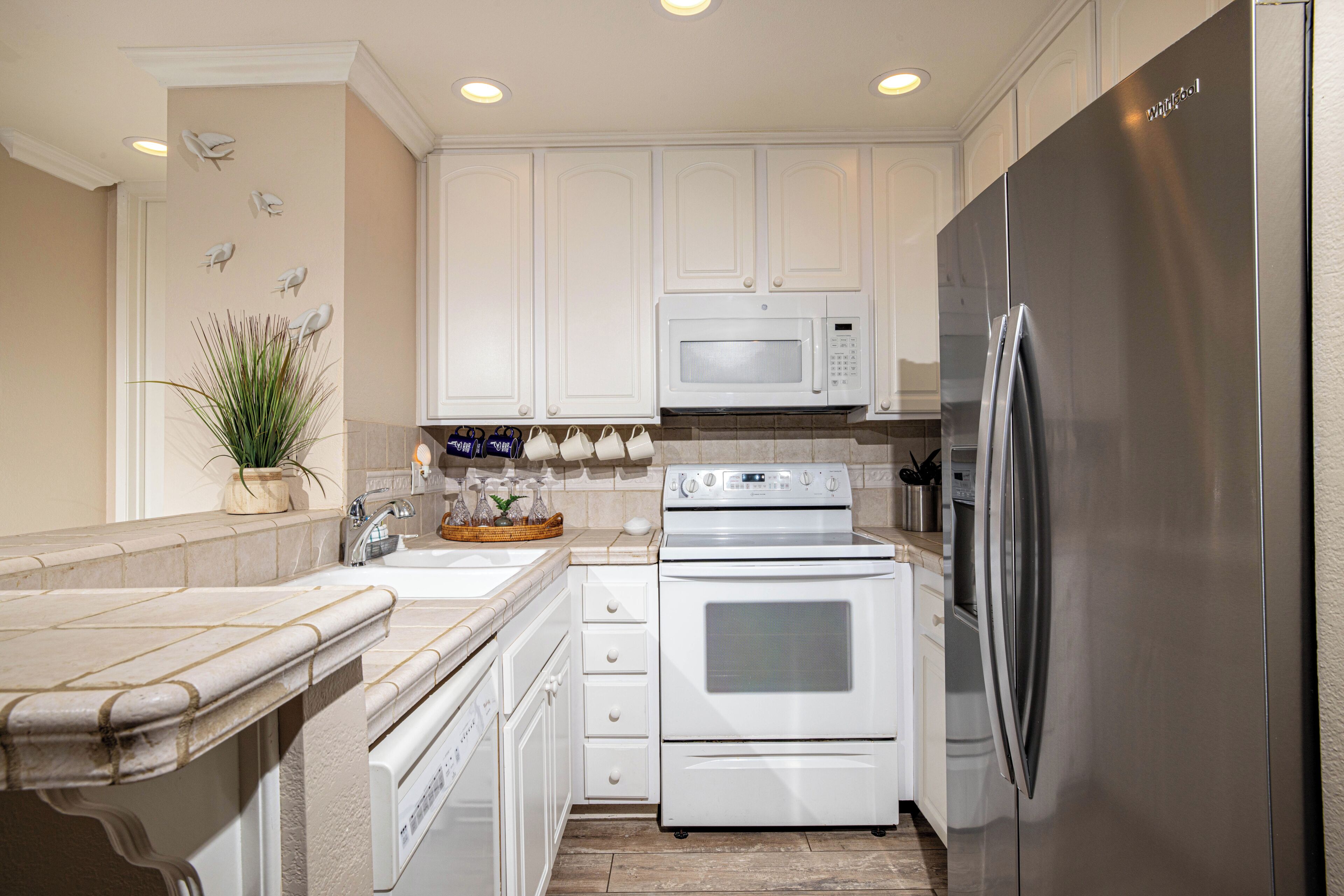 A modern kitchen with white cabinetry, stainless steel appliances, and a tiled backsplash.