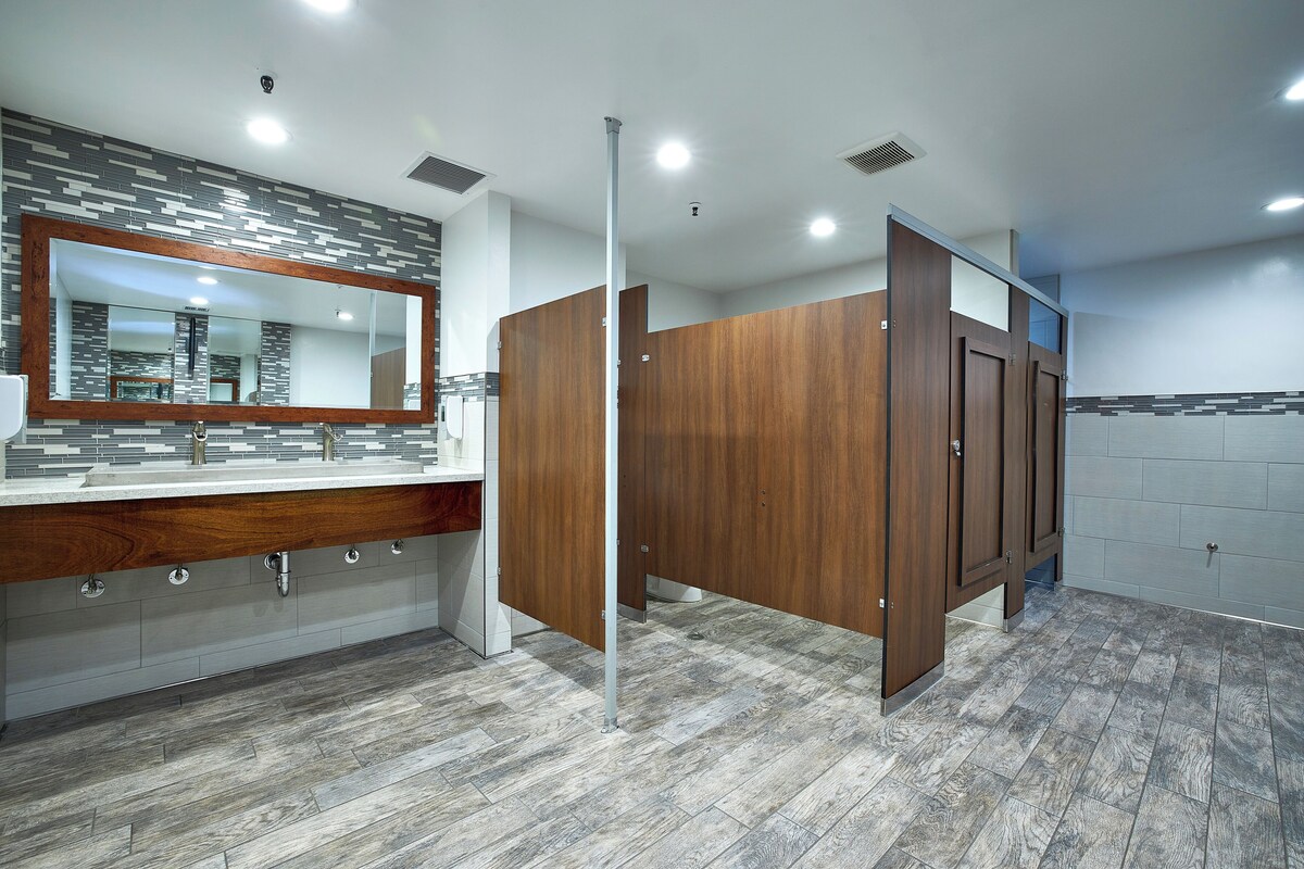 A modern bathroom with a large mirror, wooden vanity, and a tiled floor.