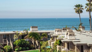 Ein Hotel direkt am Strand mit mehrstöckigen Gebäuden, einem Poolbereich und Palmen.