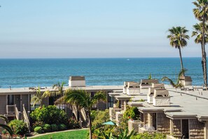 A beachfront hotel with multiple-story buildings, a pool area, and palm trees. - Oceanside Beach Condos (Oceanside)