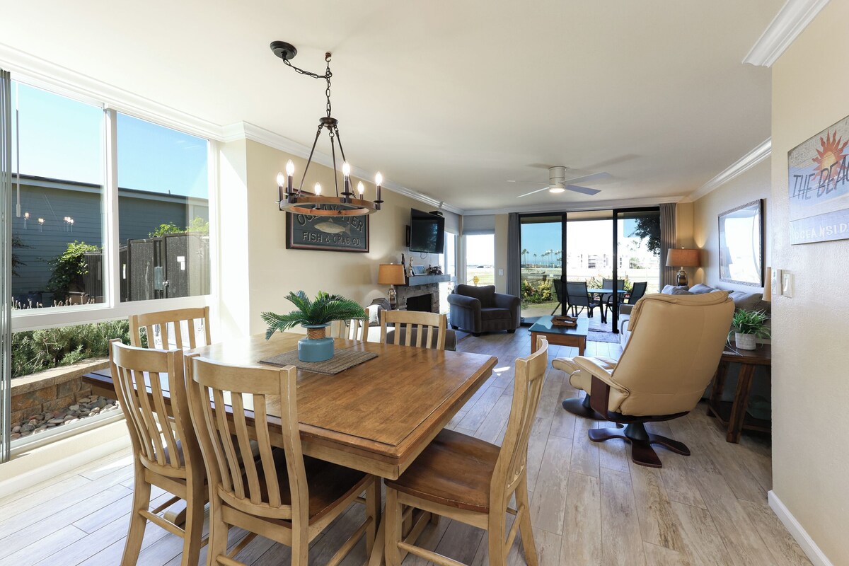 A spacious living area with a wooden dining table, comfortable seating, and a view of the outdoors.