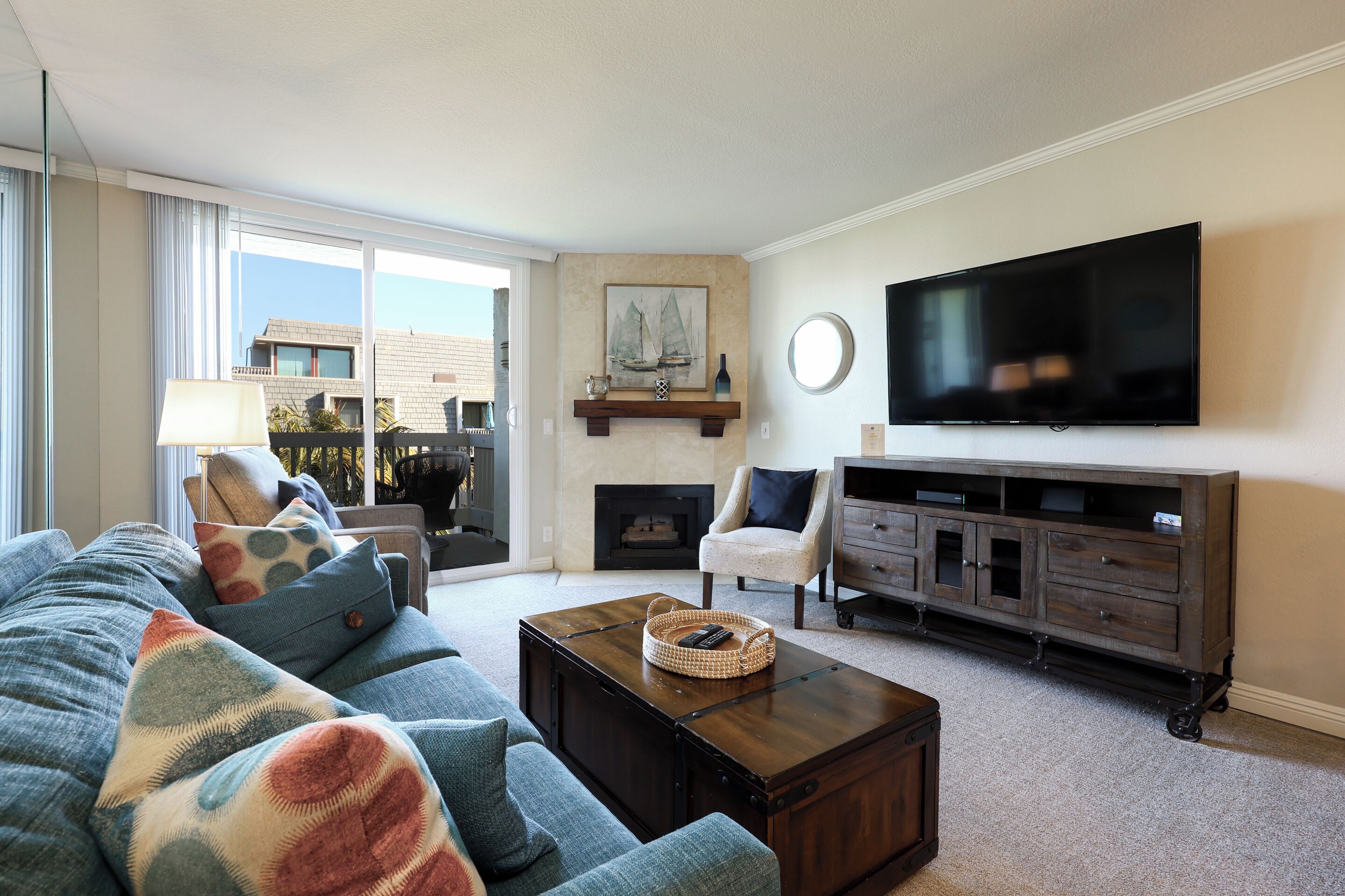 Ein Wohnzimmer mit großem Fenster, einer Couch, einem Couchtisch, einem Fernseher und einem Kamin.