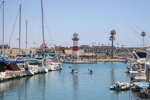 A marina with boats, a lighthouse, and a building with a red and white striped roof. - Oceanside Beach Condos (Oceanside)