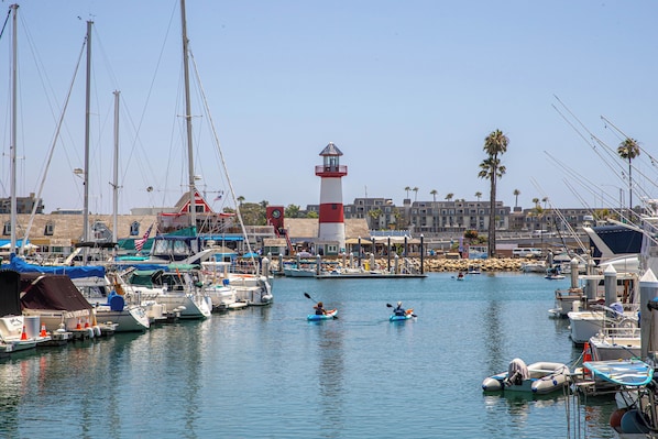 Marina com barcos, farol e um edifício com telhado vermelho.