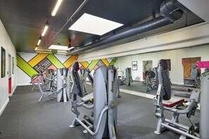 A gym with various exercise machines, a large mirror, and motivational posters on the walls. - Oceanside Beach Condos (Oceanside)