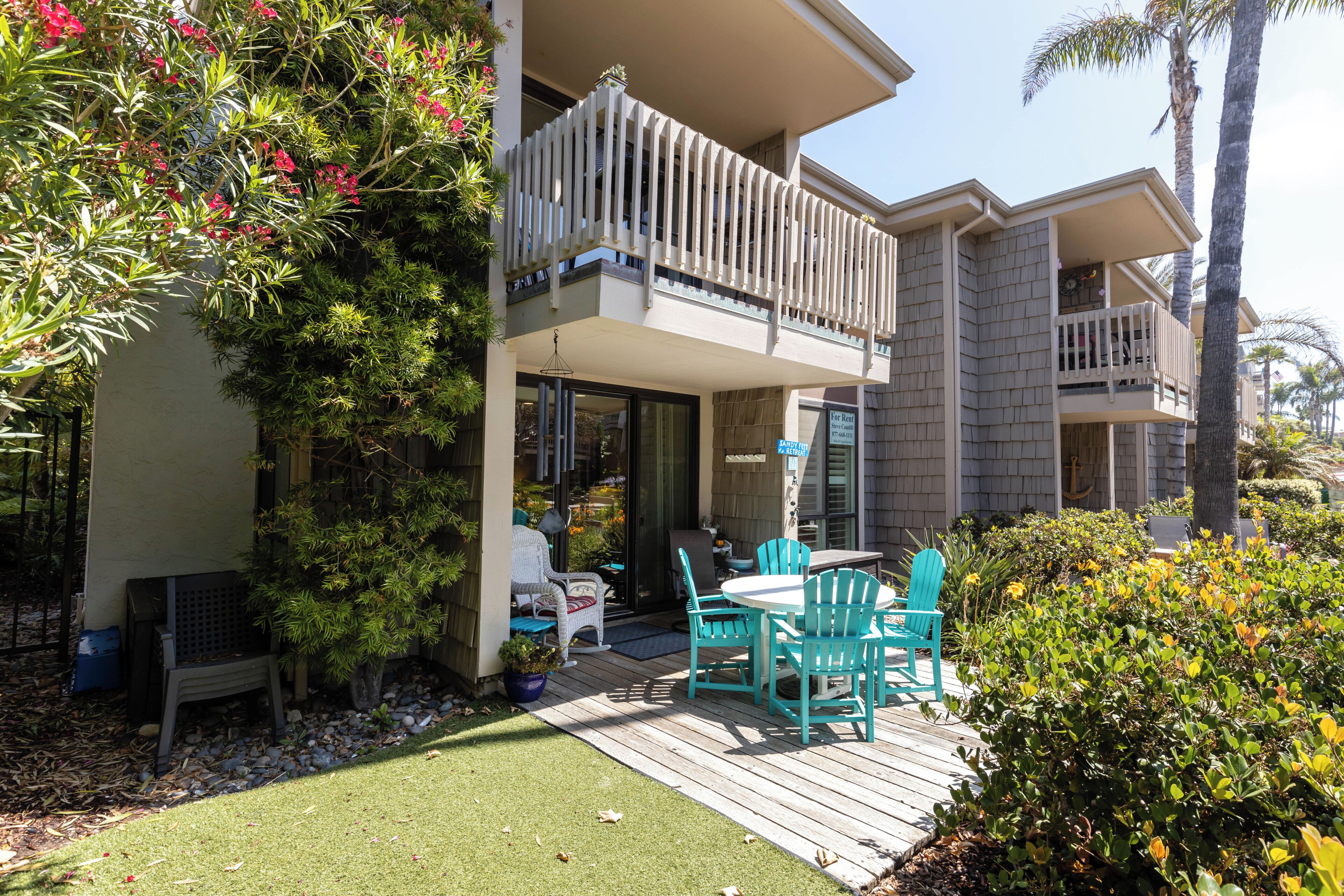 A two-story building with a balcony, outdoor seating area, and a well-maintained garden.