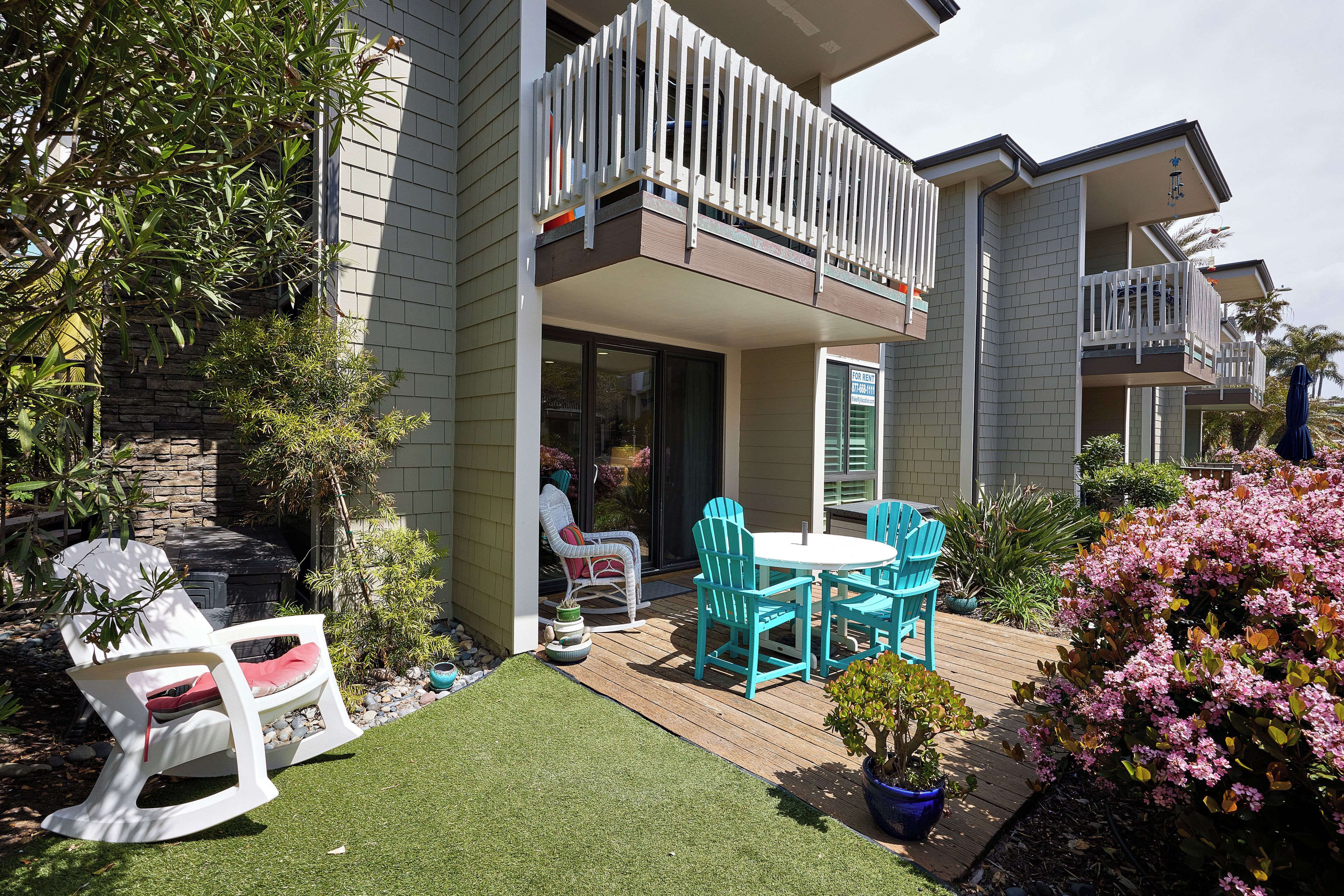 A residential building with a balcony, outdoor seating area, and a garden.
