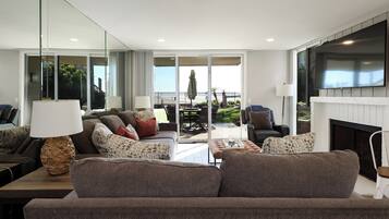 A modern living room with a sofa, armchairs, a coffee table, and a fireplace.
