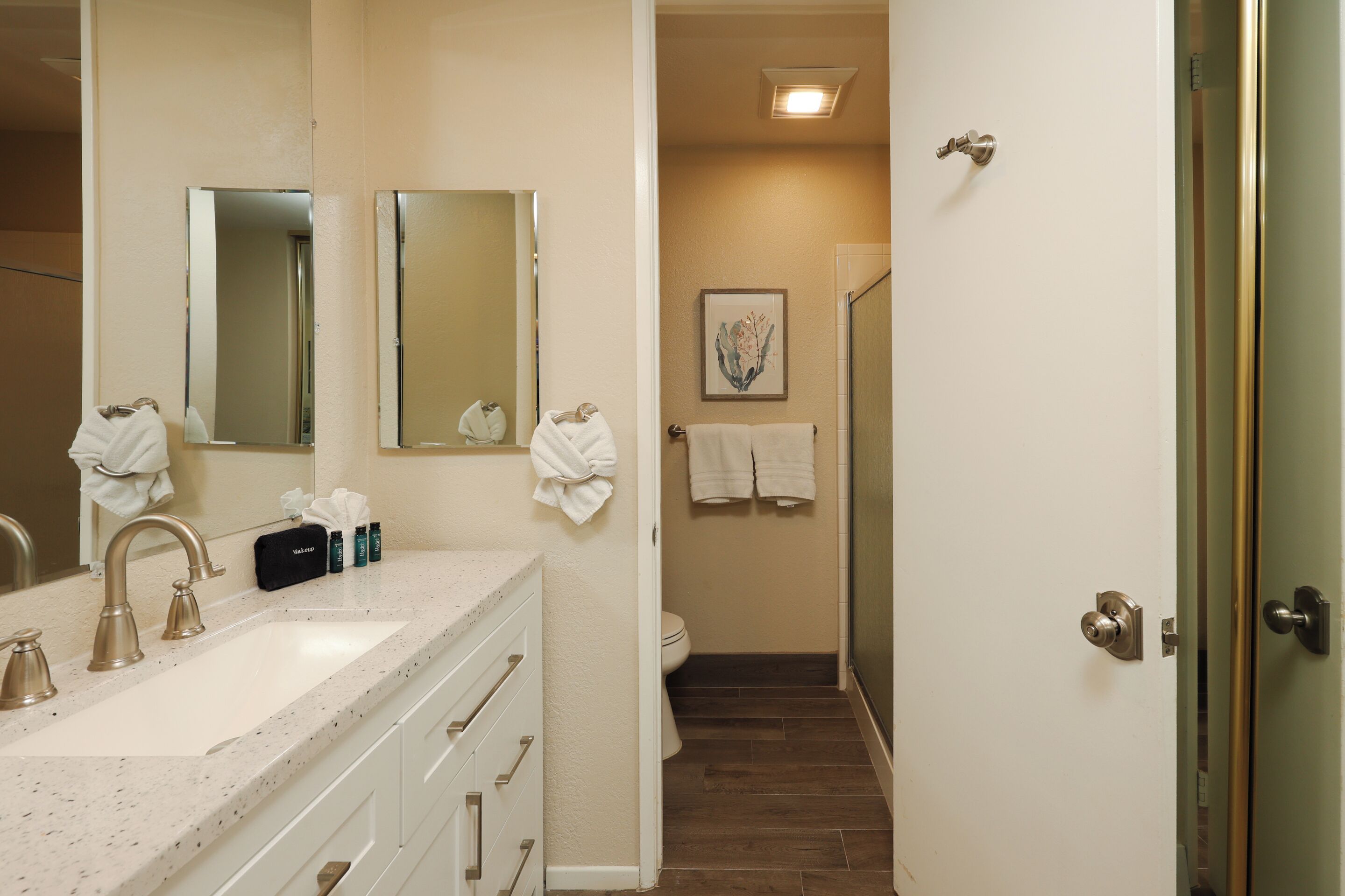 A bathroom with a sink, mirrors, a shower, and a toilet.