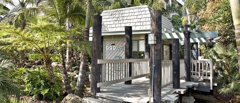 Un pequeño edificio rústico con un letrero que dice "999 North Pacific", rodeado de abundante follaje y un sendero de piedra.