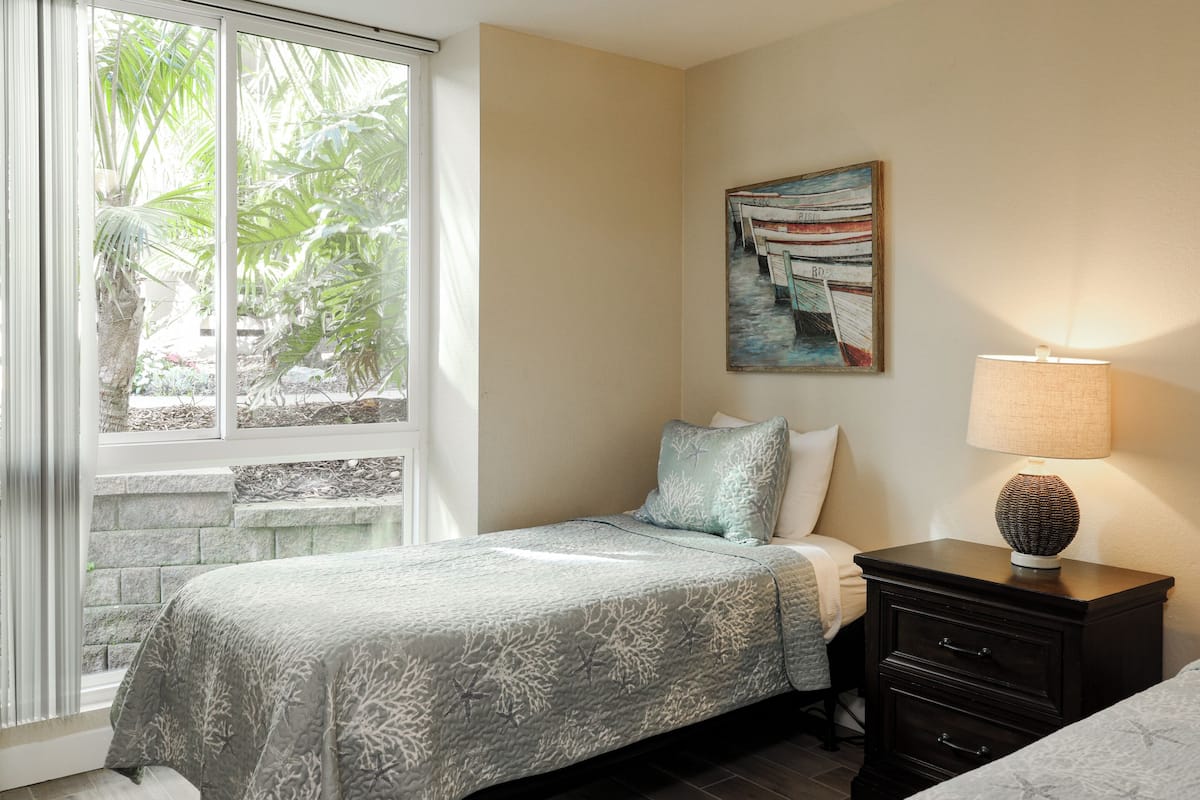 A bedroom with a bed, a nightstand, a lamp, and a painting on the wall.