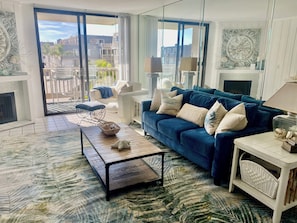 A living room with a blue sofa, white armchairs, a coffee table, and a fireplace. - Oceanside Beach Condos (Oceanside)