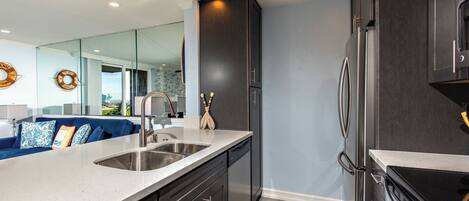 A modern kitchen with dark cabinetry, stainless steel appliances, and a large island with a sink.