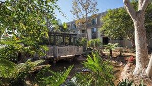 Une cour avec un pont en bois, un petit étang et un bâtiment doté de balcons.