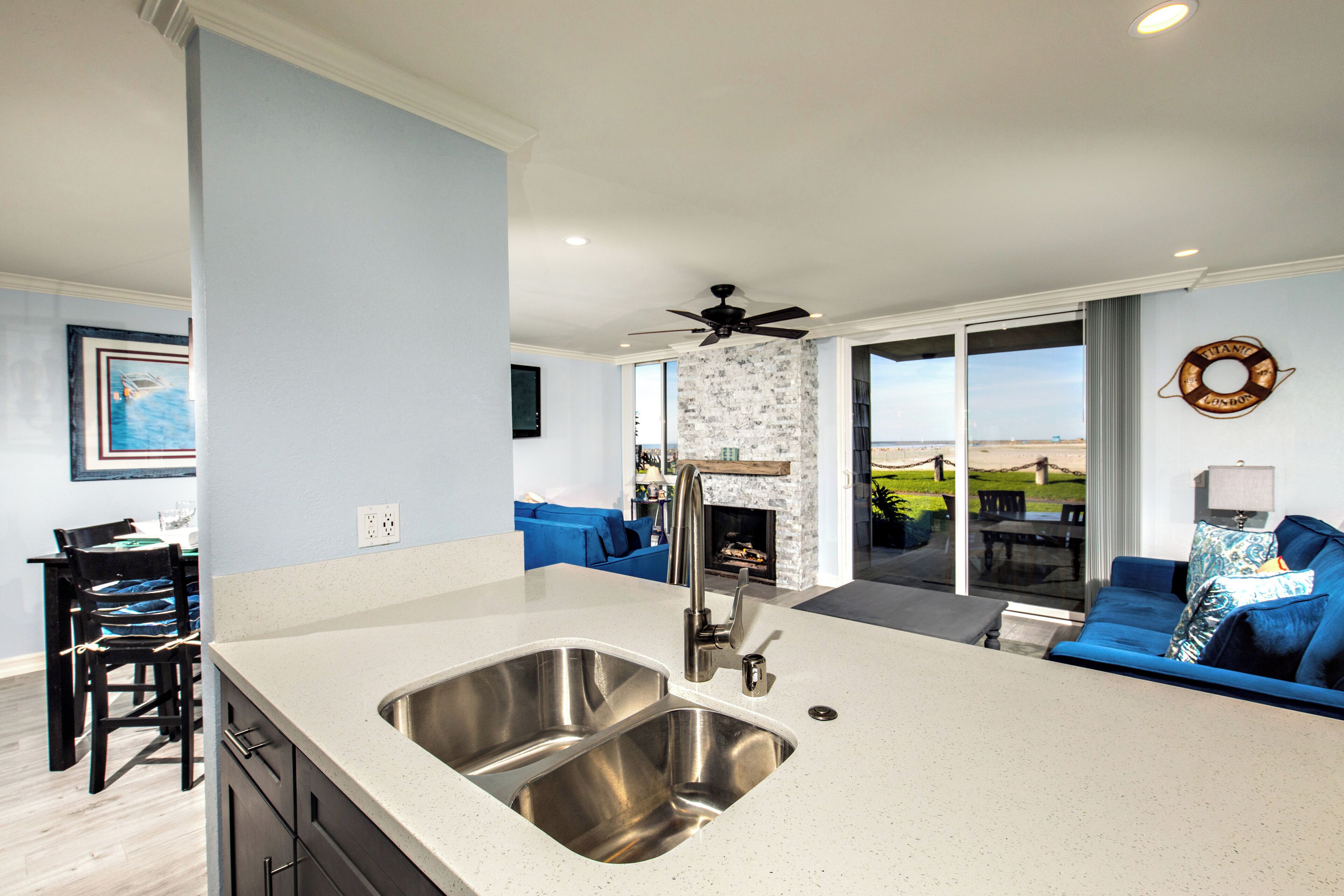 A modern kitchen with a large island, a built-in fireplace, and a view of the outdoors.