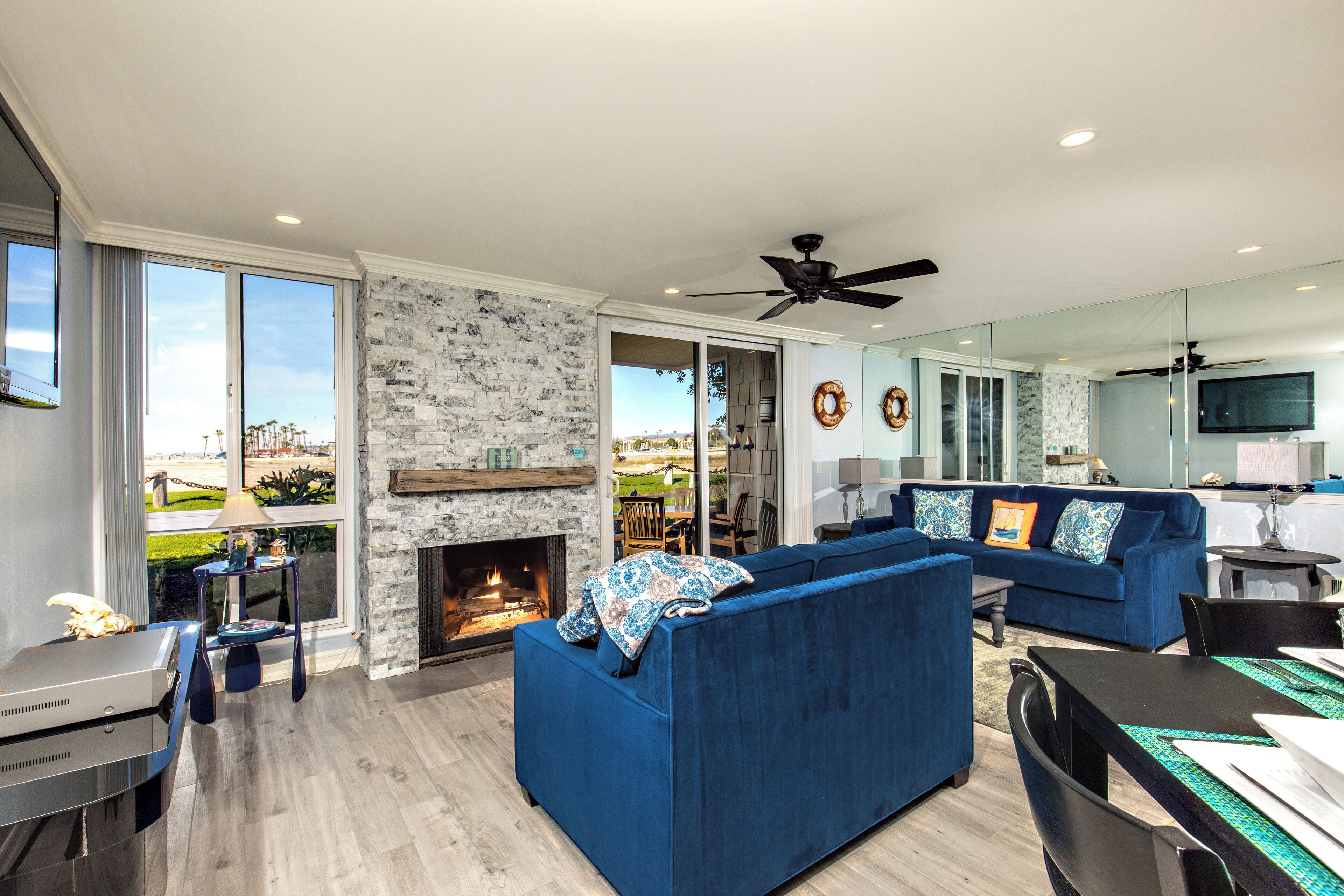 Un salón espacioso con chimenea, un sofá azul y una zona de comedor.