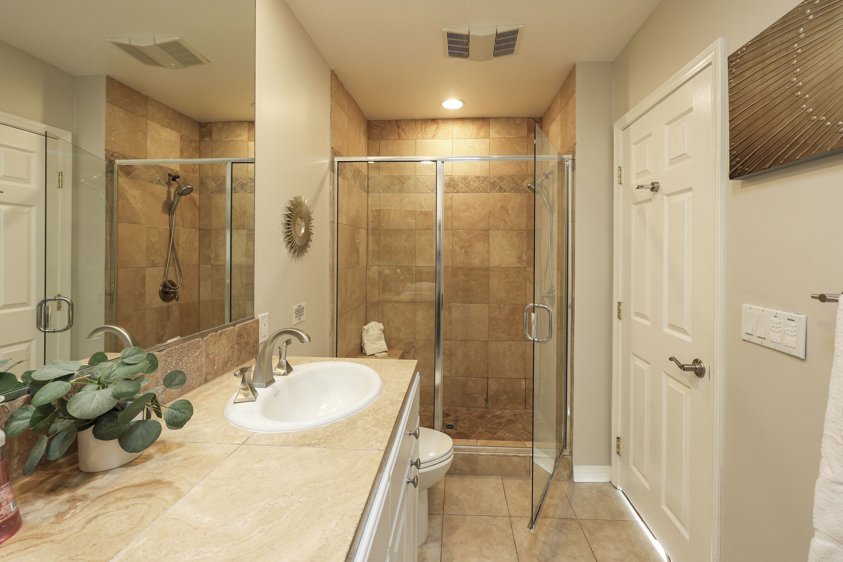 A bathroom with a glass-enclosed shower, a sink, and a toilet.