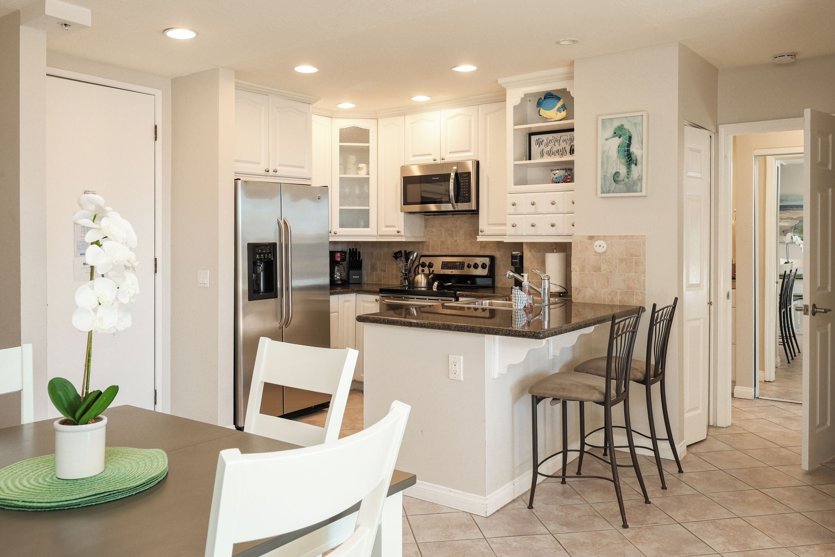 A modern kitchen with white cabinets, stainless steel appliances, and a central island with bar stools.