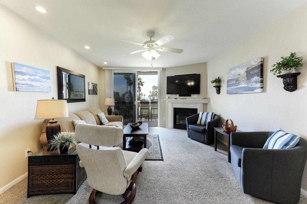 A living room with a ceiling fan, a fireplace, and a television.