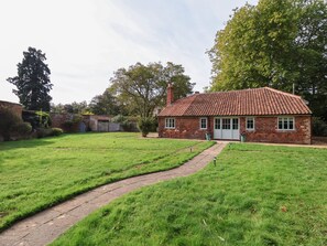 A brick house with a tiled roof, a paved pathway leading to the entrance, and a grassy yard. - Rookery Cottage (Saxmundham)