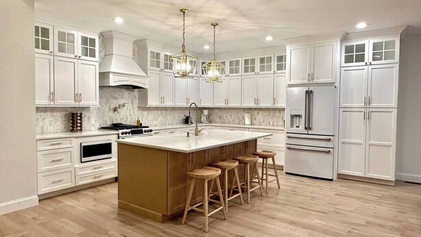 A modern kitchen with white cabinetry, a central island with stools, a built-in oven, and a stainless steel refrigerator. - New Farmhouse-Hot Tub, King Beds, Game Room, Pro Golf Sim & Amazing Valley View! (Montgomery)