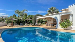 A pool area with lounge chairs and umbrellas, surrounded by palm trees and a white building with an archway. - ★Luxury Villa Heated Pool, walk to São Rafael Beach, Albufeira (Albufeira)