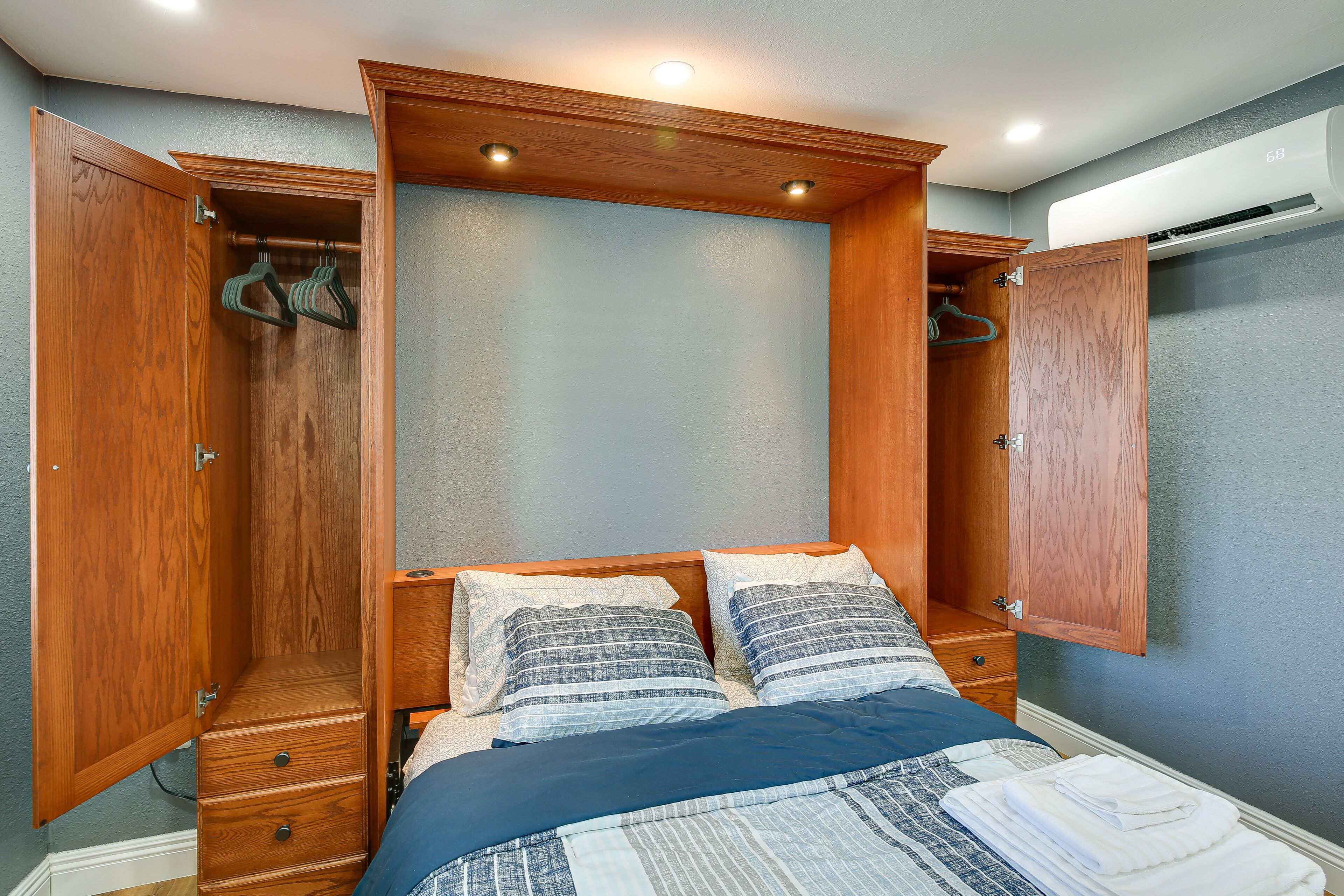 Un dormitorio con cama, armario de madera y vestidor abierto.