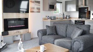 A modern living room with a flat-screen TV, grey sofa, and a coffee table. - Patrington Haven is a pristine lodge park with an array of facilities. (Patrington, near Hull)