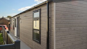 A mobile home with a wooden exterior, a front door, and a window. - Patrington Haven is a pristine lodge park with an array of facilities. (Patrington, near Hull)