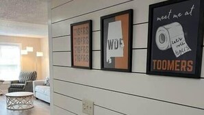 A hallway with framed wall art, a white couch, and a round coffee table.