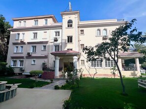 A large, multi-story building with a symmetrical facade, a central entrance with columns, and a small porch.