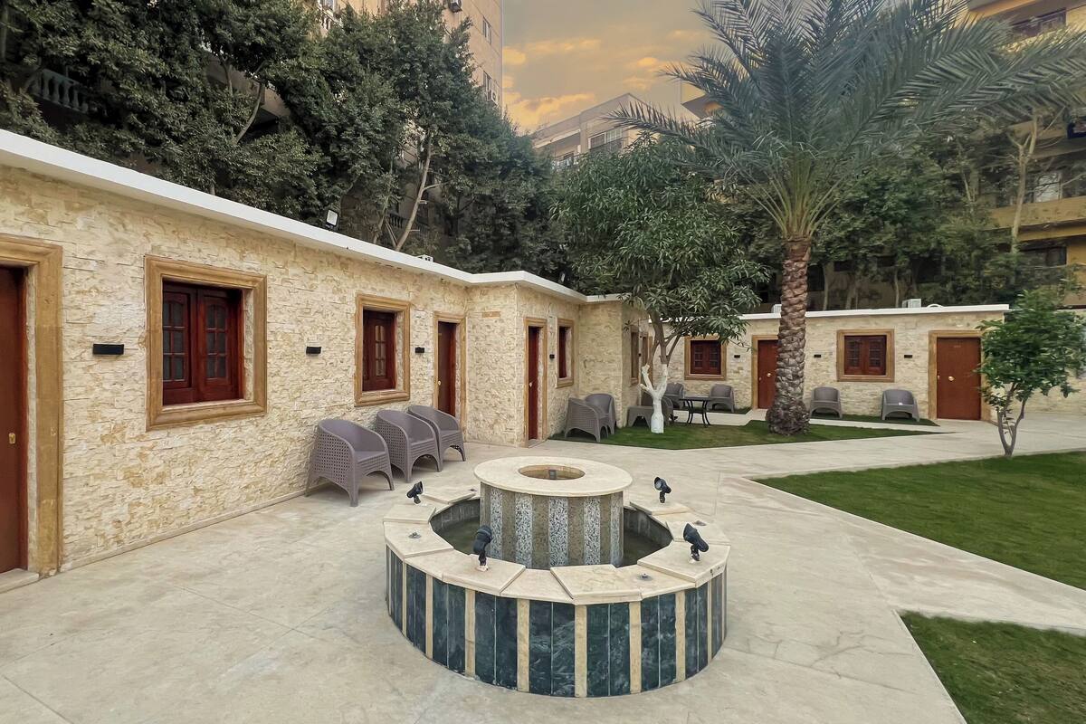 A courtyard with stone walls, multiple doors, and outdoor seating.