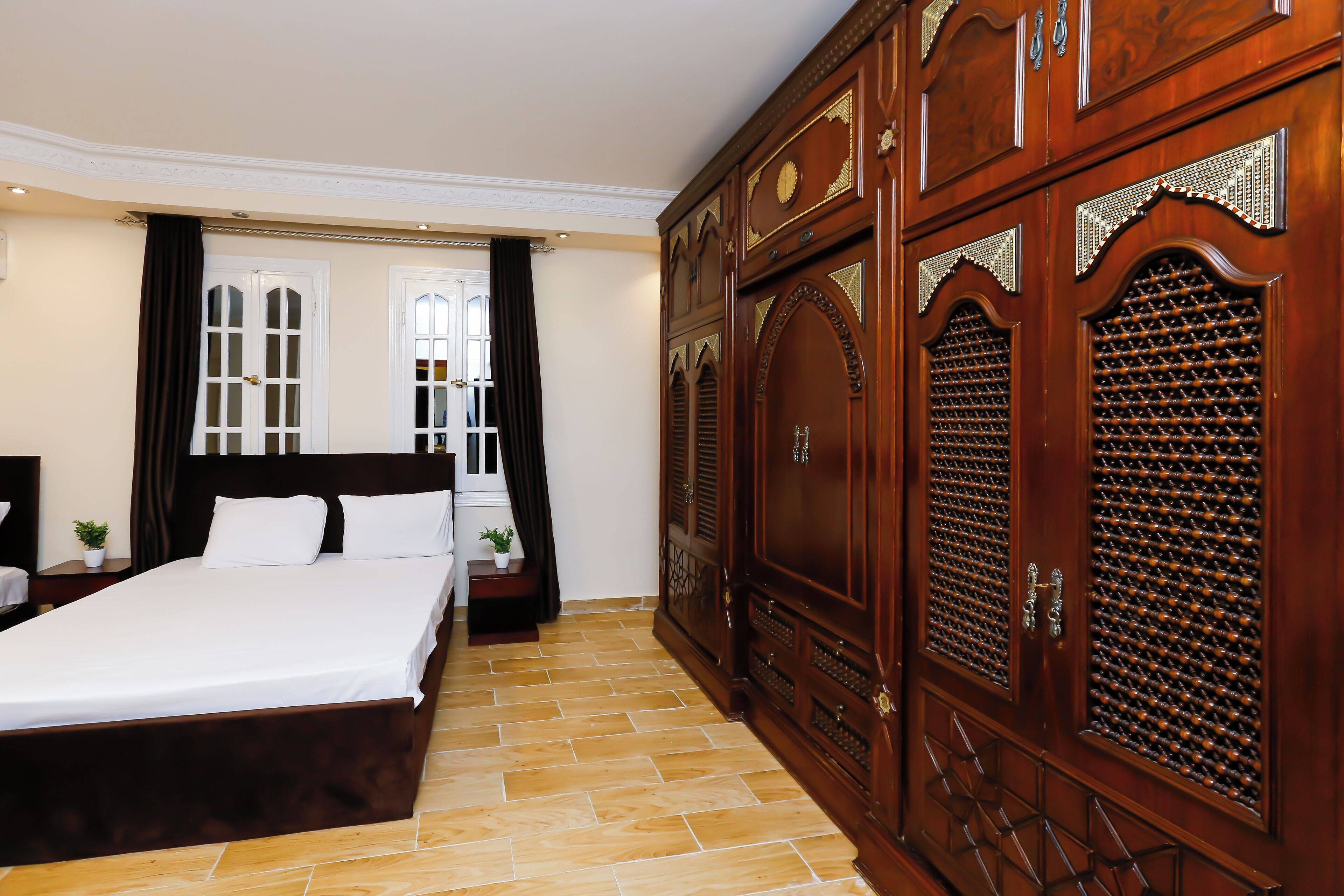 Habitación de hotel con una cama grande, un armario y una ventana con cortinas.