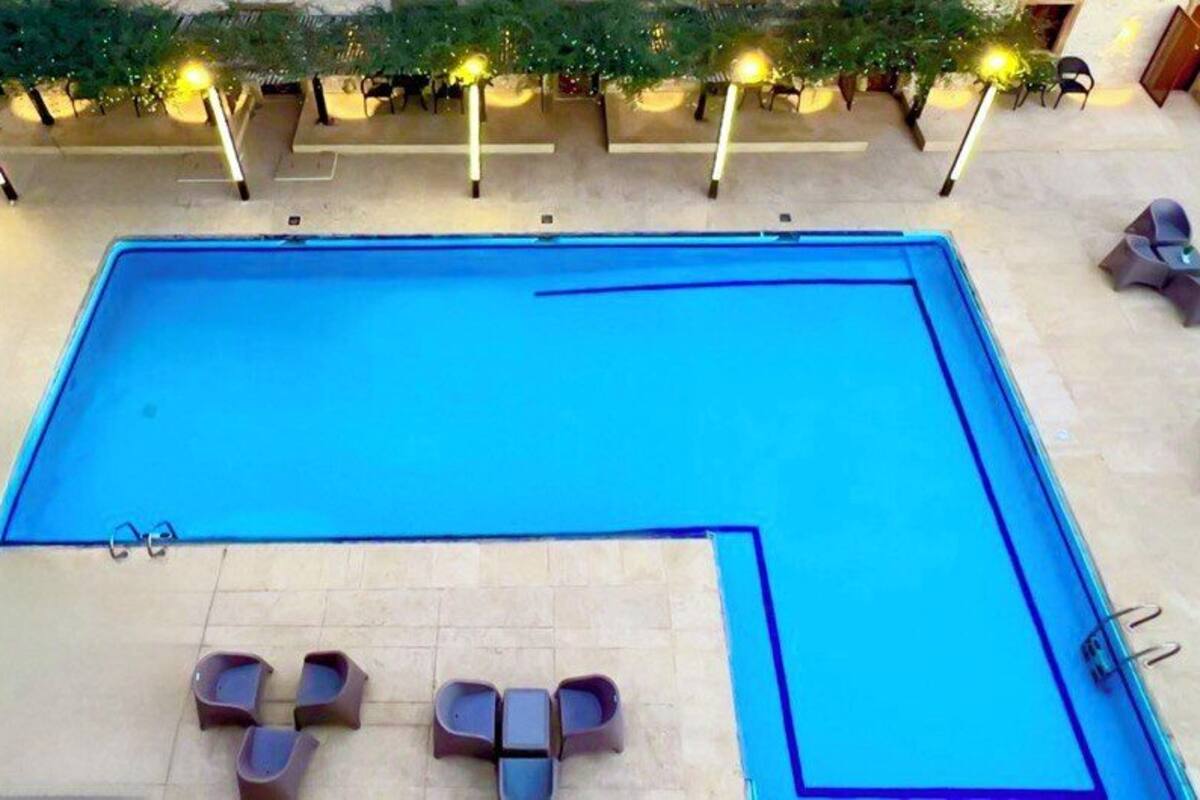 A rectangular swimming pool with a smaller circular pool adjacent to it, surrounded by lounge chairs and a small table.