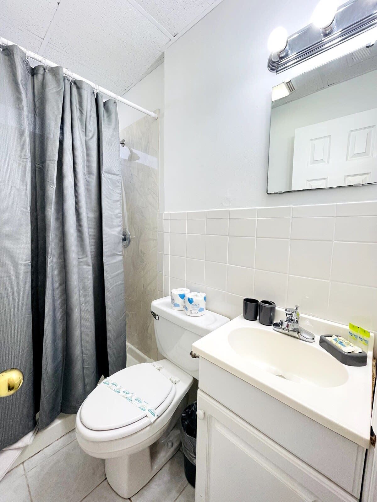 A bathroom with a toilet, sink, and shower curtain.