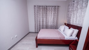 Ein Schlafzimmer mit einem hölzernen Bett, weißer Bettwäsche und einem Fenster mit Vorhängen.