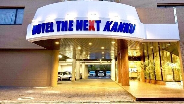 A hotel entrance with a curved sign reading "HOTEL THE NEXT KANKU". - HOTEL THE NEXT KANKU (Sennan)